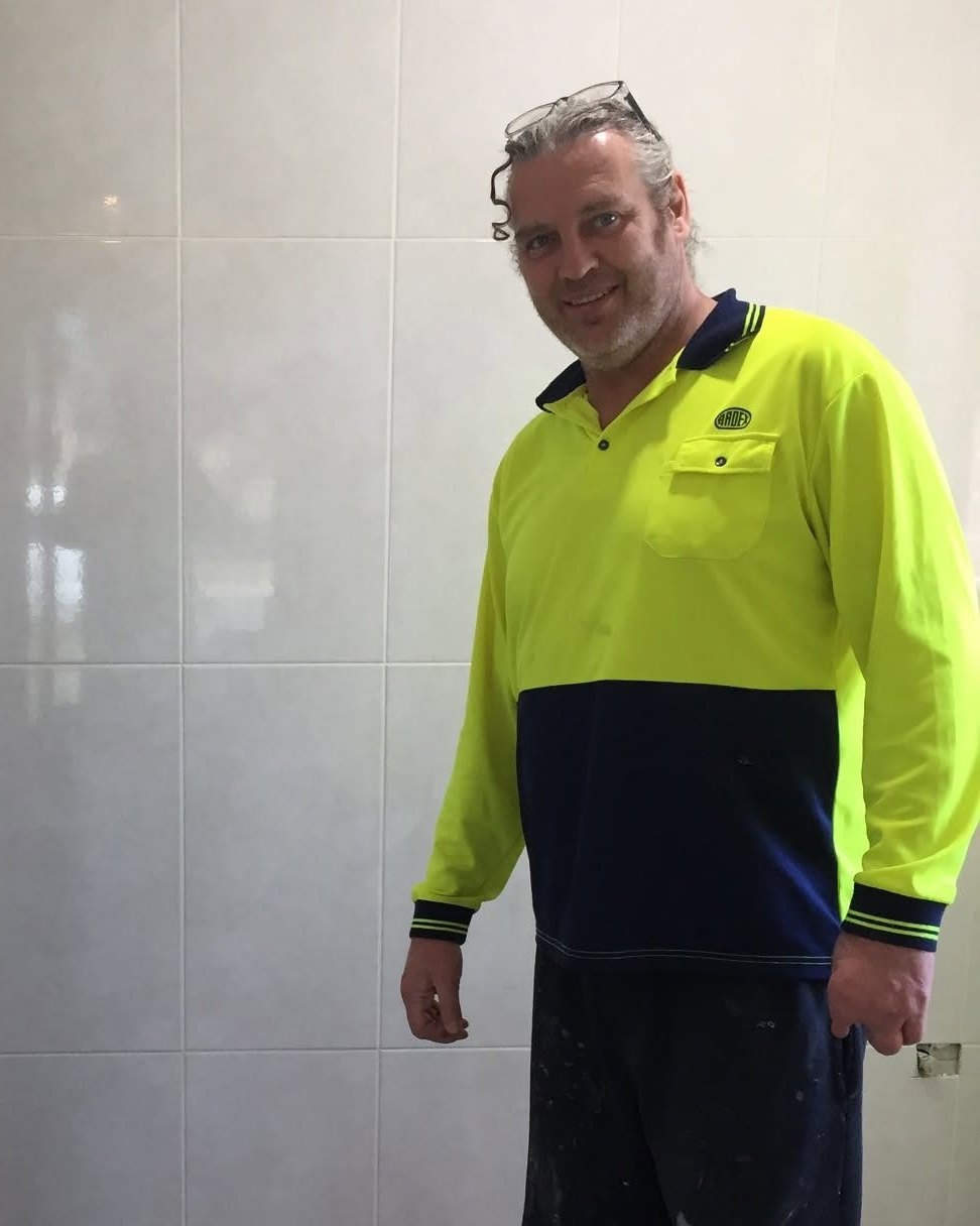 Michael standing beside a newly tiled wall