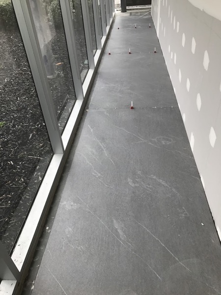A large-format grey floor tile running up to a full-height glass door