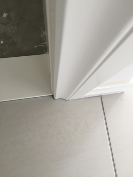 A newly tiled floor meeting the plastered corner of a freshly built wall