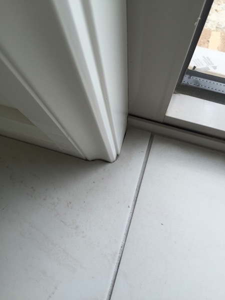 A tiled floor running under a wall return and up to a set of glass doors