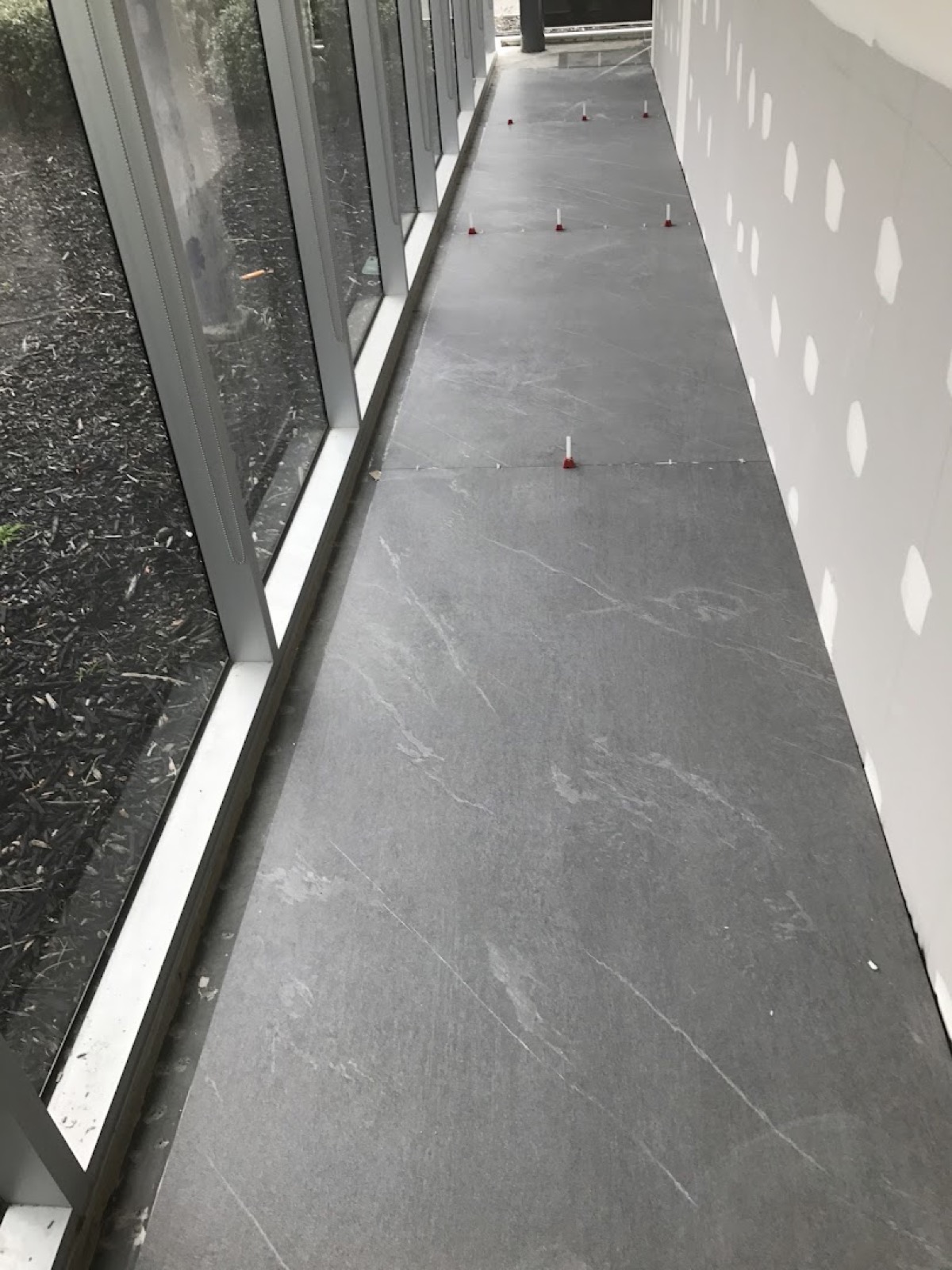 A large-format grey floor tile running up to a full-height glass door
