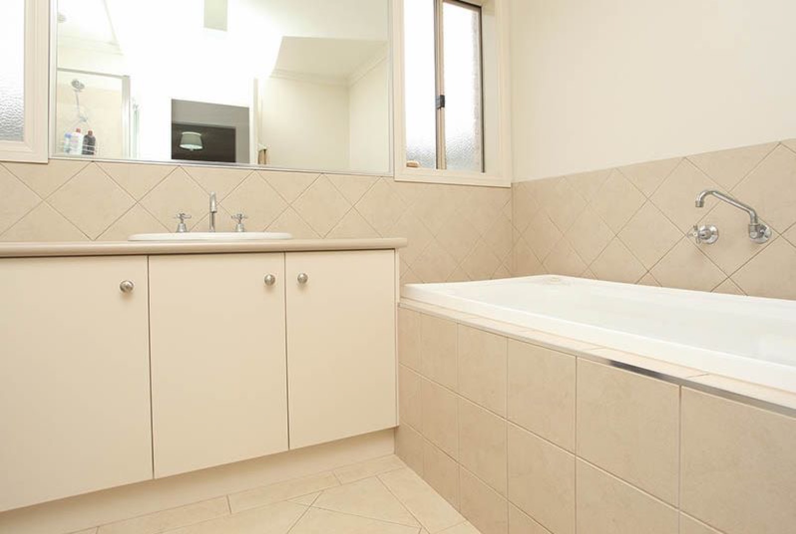 A bathroom with a built-in bath, a tiled hob and a floor-to-ceiling tiled wall