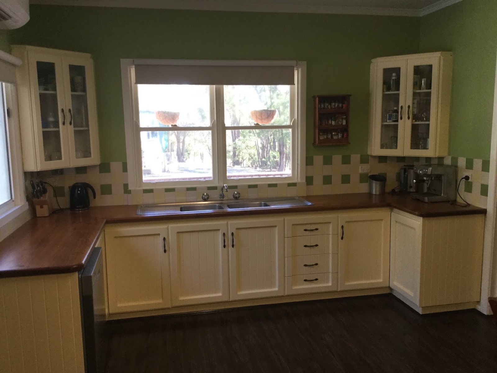 A kitchen with a mosaic tile splashback running behind the sink and bench