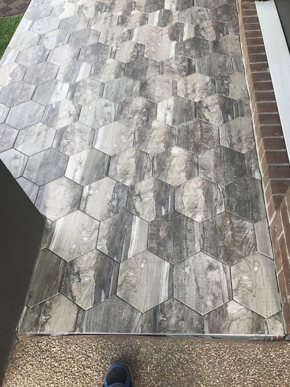 Hexagon stone-look tiles laid in a honeycomb pattern across a wall beside a dark panel
